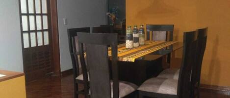 A dining area with a wooden table, four chairs, and a hanging pendant light.