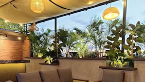 Un espace extérieur accueillant, avec une table et des chaises en bois, entouré d’une végétation luxuriante et d’un mur de briques.