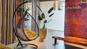 Un intérieur moderne agrémenté d’un fauteuil suspendu, d’une plante en pot et d’un banc en bois.
