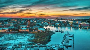 A coastal town at sunset with a marina, waterfront buildings, and boats docked.