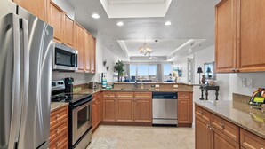 A modern kitchen with stainless steel appliances, wooden cabinets, a dishwasher, and a large island with a sink.