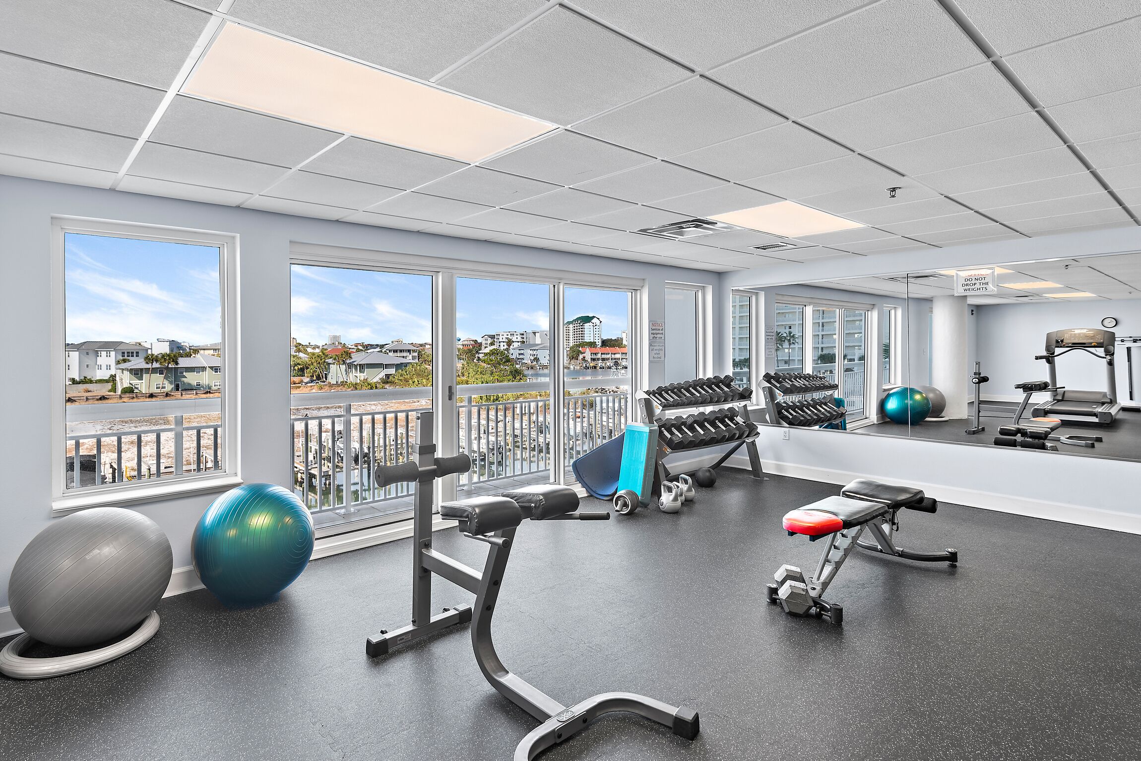 A gym with exercise equipment, large windows, and a view of buildings.