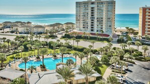 A resort with a large pool, palm trees, and a view of the ocean.