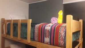 En våningssäng med ett färgglatt täcke och en hoprullad handduk på den övre våningen.