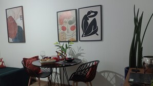 Ein Essbereich mit einem runden Tisch, zwei Stühlen, einem Blumentopf und einem Laptop auf Holztisch.
