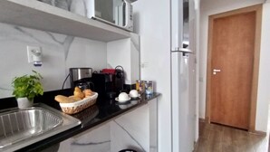 Eine moderne Küche mit Marmorarbeitsplatte, einer Kaffeemaschine, einem Toaster und einem Brotkorb.