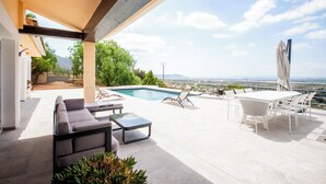 Una moderna terrazza esterna con piscina, posti a sedere e un tavolo.