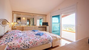 Una camera da letto con un letto, una scrivania, una televisione, un balcone con vista e un grande specchio.