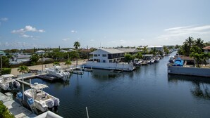 Un puerto deportivo con barcos amarrados, un edificio blanco y palmeras.