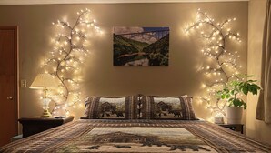 Une chambre à coucher avec un lit, une lampe, un tableau au mur et une plante en pot.