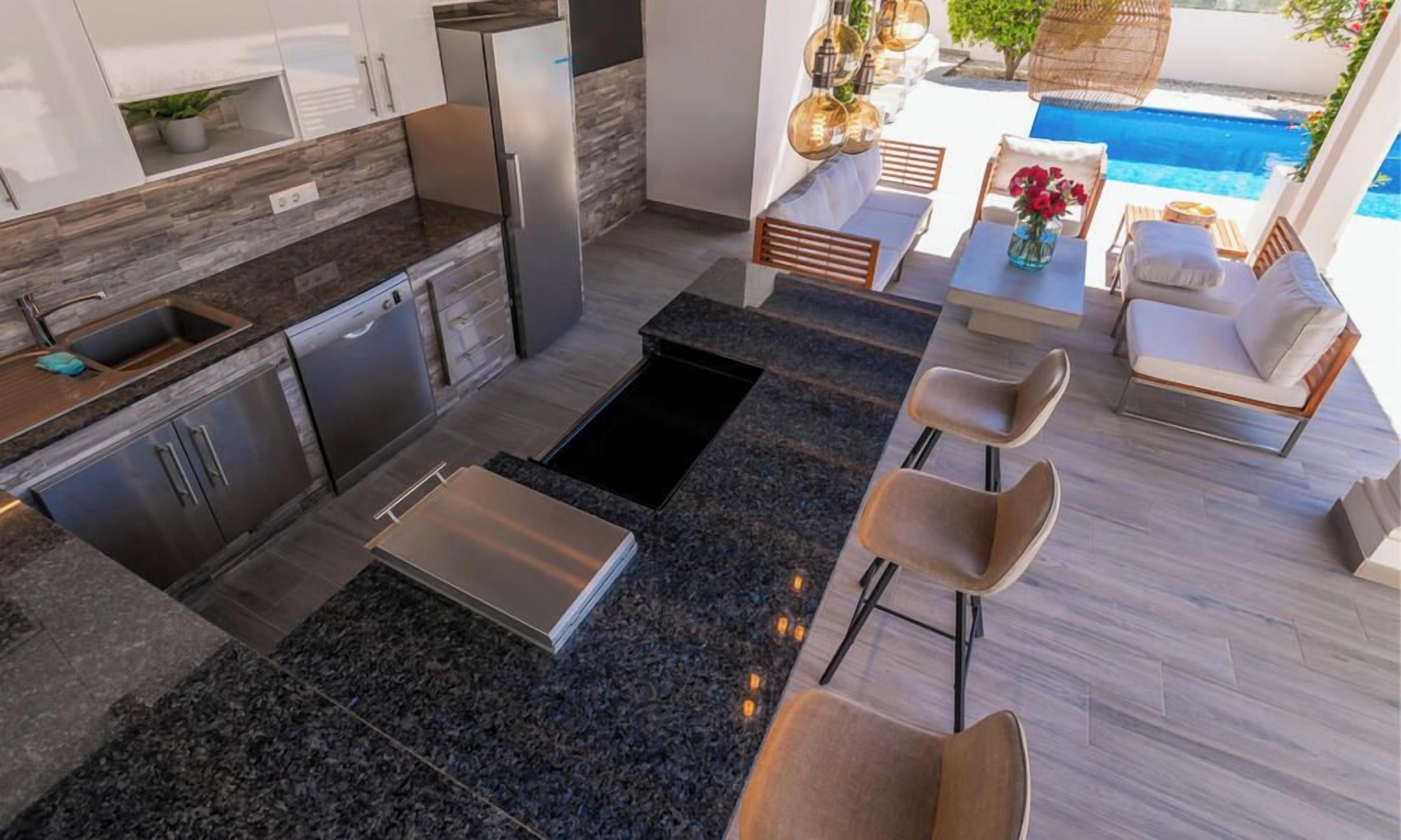 A modern kitchen with granite countertops, stainless steel appliances, and a dining area with a pool view.