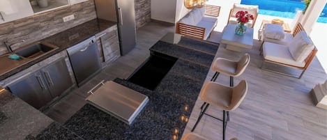 A modern kitchen with granite countertops, stainless steel appliances, and a dining area with a pool view.
