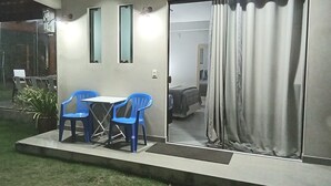 Una habitación con una cama, un ventanal corredero y una pequeña mesa con dos sillas.