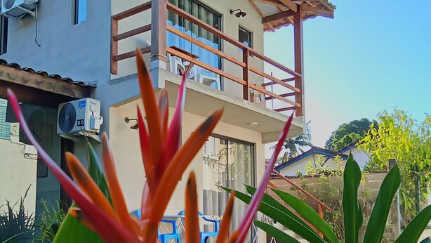 Un edificio de dos pisos con balcón, unidades de aire acondicionado y cielo despejado.