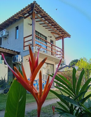 A two-story building with a balcony, air conditioning units, and a clear sky. - Ilhinha Suite in a private residential complex, 5 minutes from the beach in the heart of Ilhabela! (Ilhabela)