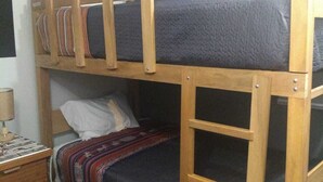 Un letto a castello con struttura in legno, una scrivania con lampada e una coperta fantasia.