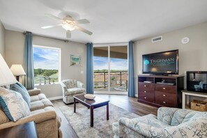 Relax in a spacious living area with a comfortable seating arrangement, flat-screen TV, and sliding door to a balcony.