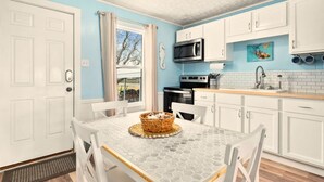 Una cocina con armarios blancos, un microondas, un horno y un lavamanos.