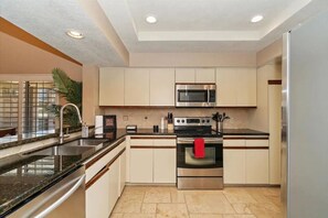 Kitchen features a central island, stainless steel oven, and granite countertop.