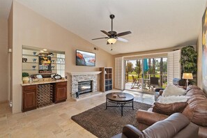 Cozy living room with a fireplace, wine rack, and TV, offering a comfortable seating area and balcony access.