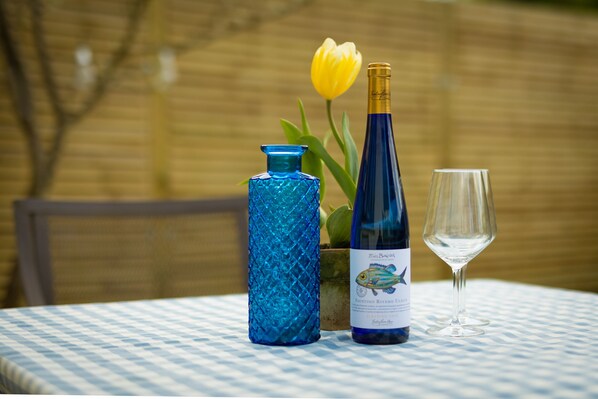 A table with a bottle of wine, a glass, and a decorative vase with a tulip.
