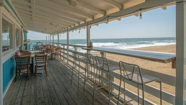 Un restaurante frente al mar con terraza y vistas al océano.