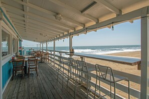 A beachside restaurant with outdoor seating overlooking the ocean.