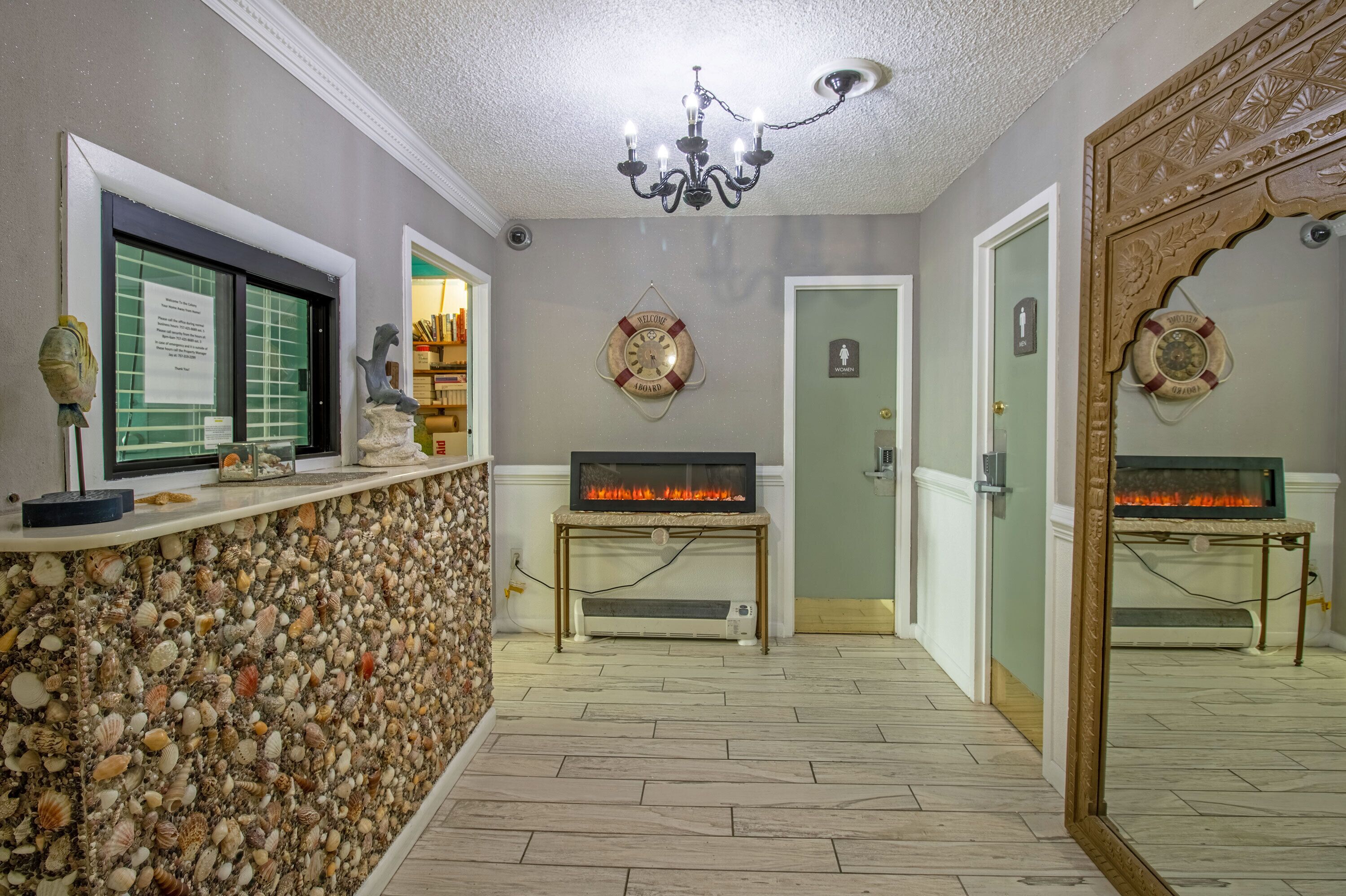 A lobby with a stone wall, a reception desk, a fireplace, and a mirror.