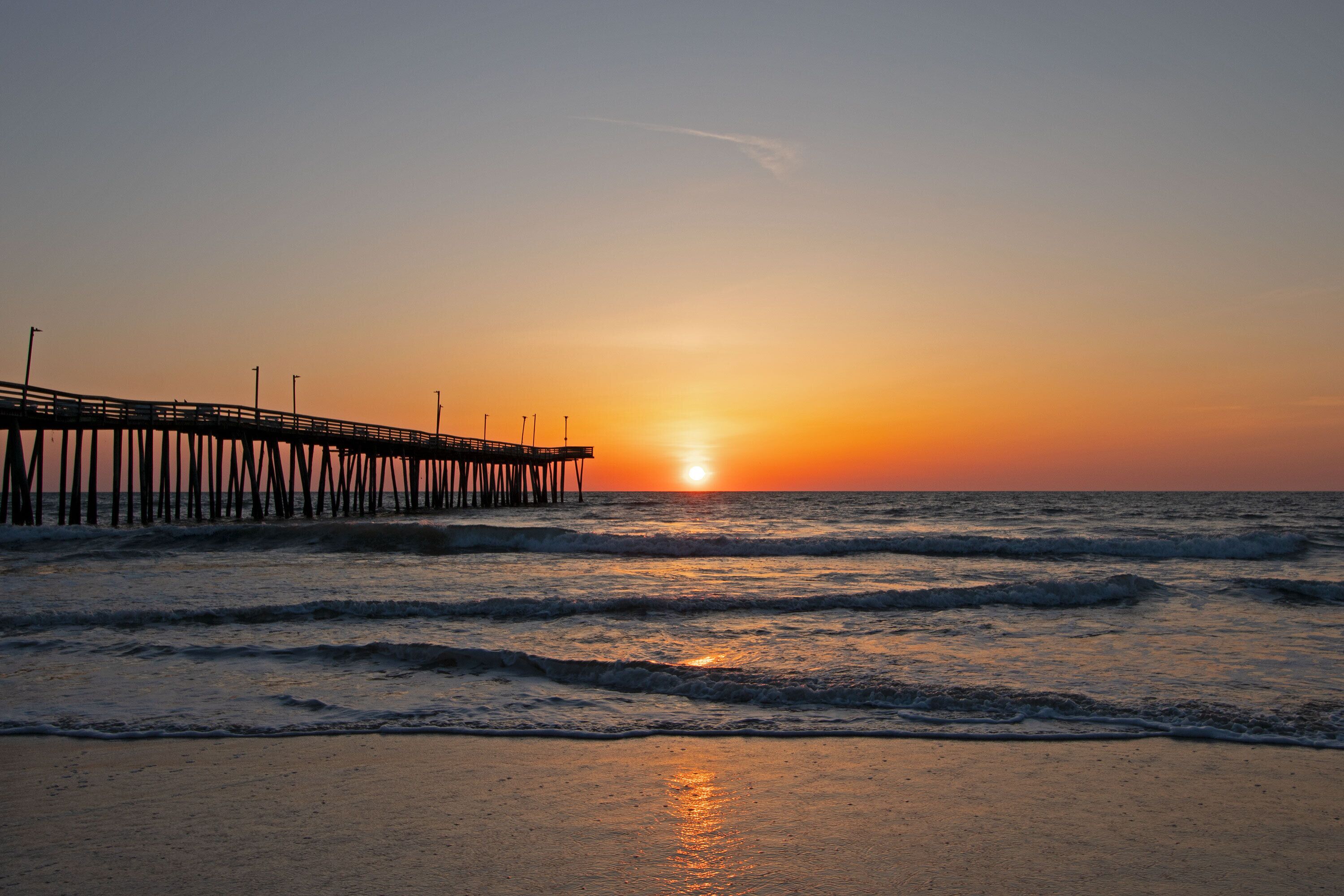A pier extending into the ocean at sunset.