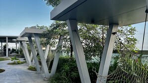 Uma área externa moderna com um caminho de concreto, estruturas metálicas e uma rede.