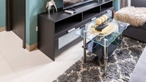 Uma sala de estar moderna com paredes verde-água, uma grande televisão de tela plana, uma mesa de centro de vidro e um móvel de entretenimento escuro.