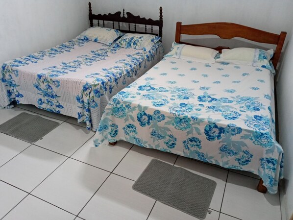 Two single beds with wooden headboards, a tiled floor, and a grey mat in front of each bed. - Casa na Praia do Atalaia em Salinas (Salinópolis)