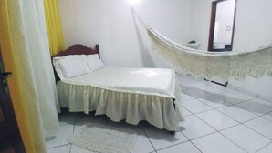 A bedroom with a bed, a hammock, a door, and a light fixture. - Casa na Praia do Atalaia em Salinas (Salinópolis)