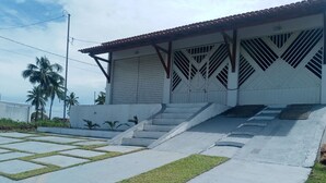 A building with a sloped roof and a staircase leading to a gated entrance. - Casa na Praia do Atalaia em Salinas (Salinópolis)