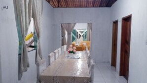 A hallway with a dining table set for two, a sofa in the background, and a door on the right. - Casa na Praia do Atalaia em Salinas (Salinópolis)