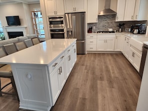 A modern kitchen with white cabinetry, stainless steel appliances, and a large island.