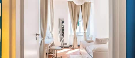 A bedroom with a bed, a desk, and a chair, with curtains and a hanging light fixture.
