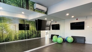 A spacious room with a large mirror, exercise balls, and a wall-mounted TV. - Luxury Airport Suite 2Bed 2Bath w/ heated parking (Calgary)