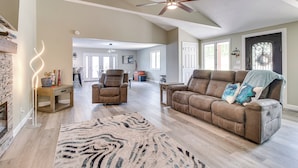 A spacious living room with a brown leather sofa, a wooden coffee table, and a zebra-patterned rug. - Serene Lakefront Mountain Home Getaway w/ Atrium! (Mountain Home)