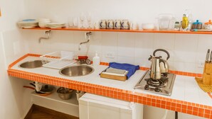 Una cocina con un lavamanos doble, una tetera y una cafetera.