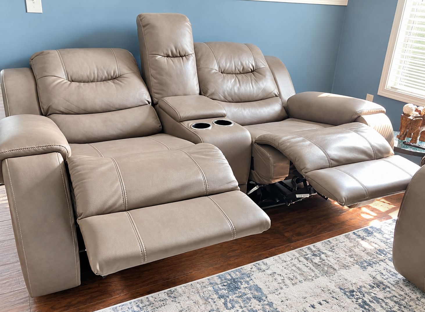 A reclining sofa with a built-in cup holder and a footrest.