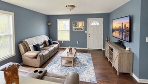 A living room with a sofa, coffee table, and a television on a stand.