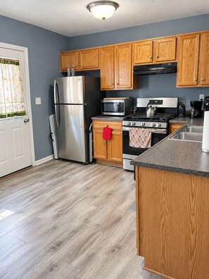 Una cocina moderna con armarios de madera, electrodomésticos de acero inoxidable y encimera gris.