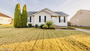 Een gelijkvloers huis met een puntgevel, een voortuin en een verzorgd gazon.