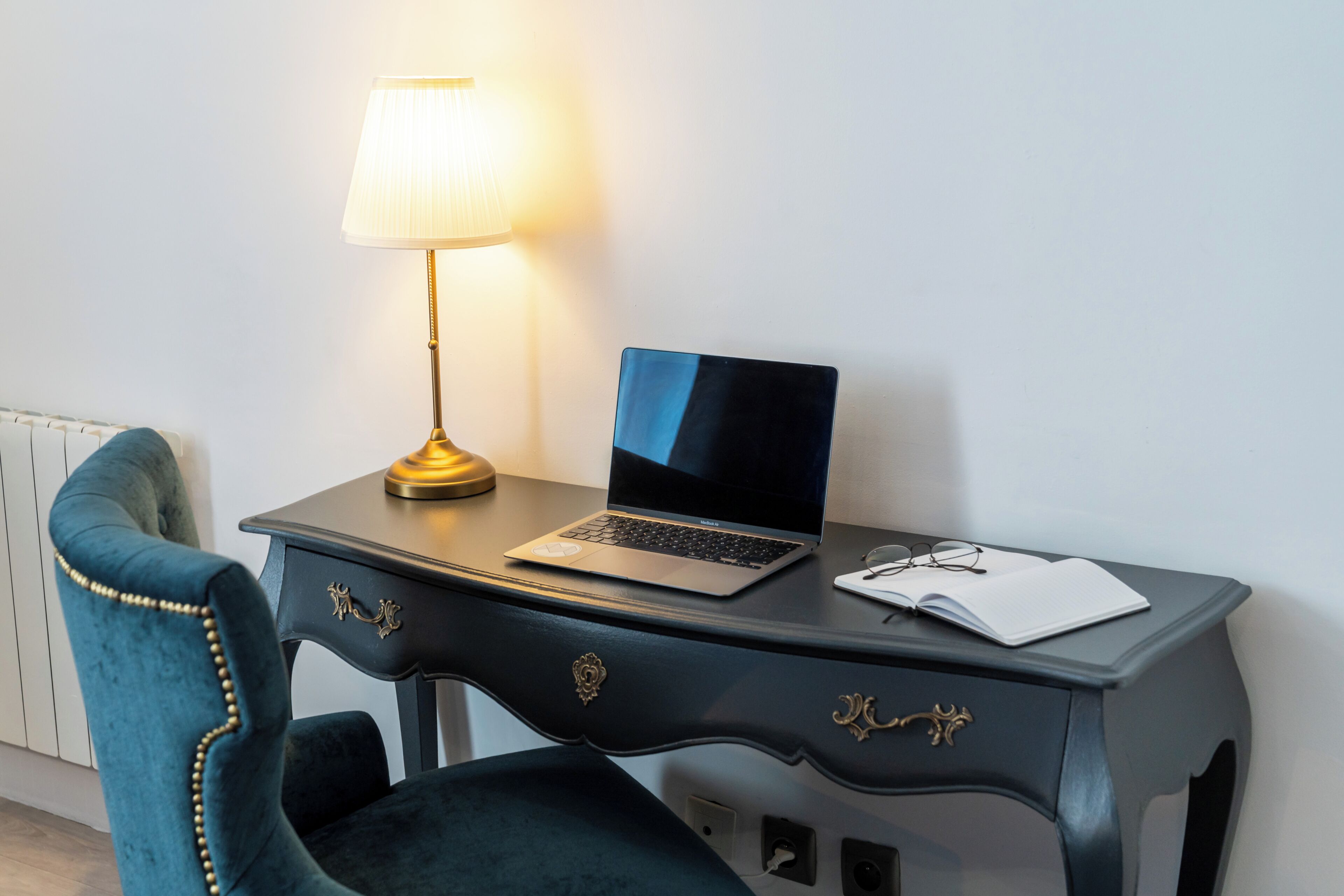 A desk with a laptop, a lamp, and a notebook.