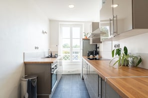 Et moderne køkken med en træbordplade, rustfrie stålgrebe og udsigt gennem døren.