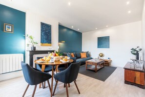 Una sala de estar moderna con comedor, que incluye un juego de sofá, una mesa de centro y una chimenea.