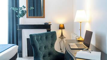 Una habitación de hotel con una cama, un escritorio con una computadora portátil, una lámpara y una silla.