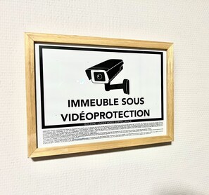 A framed sign with a surveillance camera icon and the text "IMMEUBLE SOUS VIDEOPROTECTION" indicating building under video surveillance. - Le Logis Cantilen (LAMORLAYE)