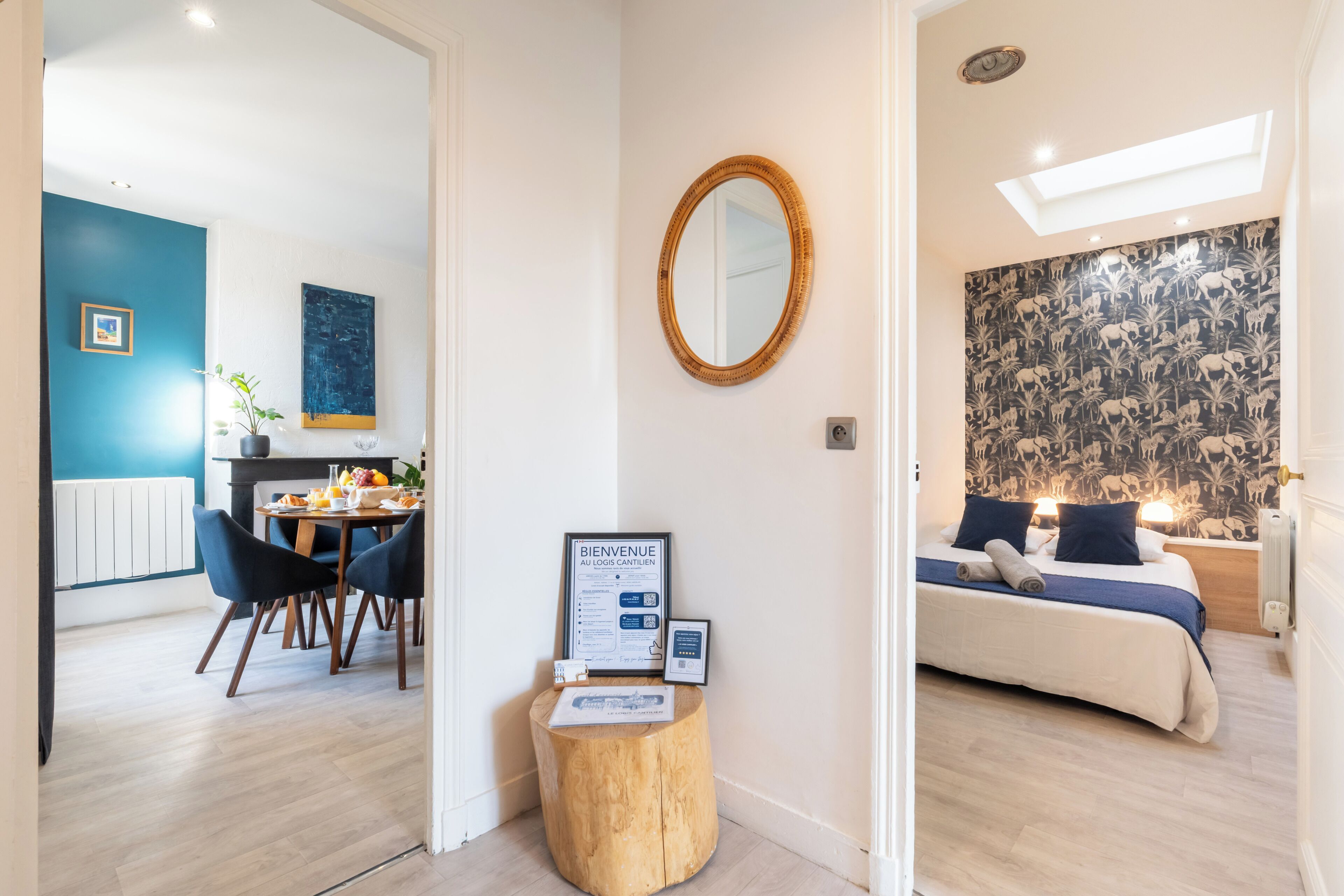 Een hotelkamer met een bed, een spiegel, een klein houten krukje en een welkomstbord.